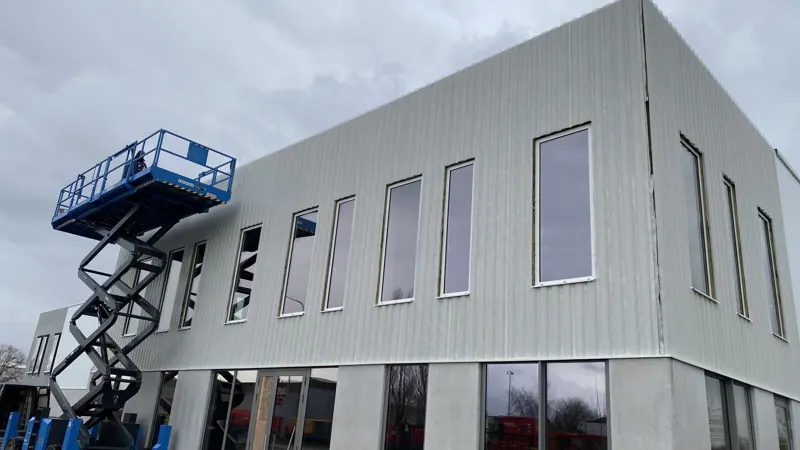 Façade en cours de bardage, équipes en nacelle